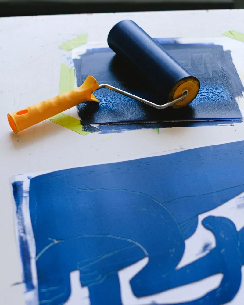 Plantilla de esténcil y rodillo de tinta sobre una mesa de taller de estampación